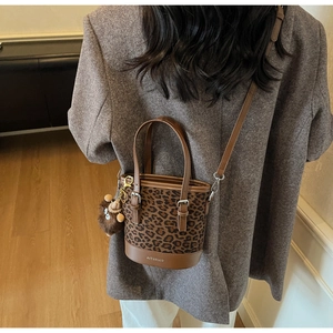 Détail d'un sac seau vintage à motif léopard avec pendentif en peluche et bandoulière