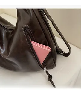 Close-up of exterior zipper pocket on dark brown faux leather tote with pink wallet inside