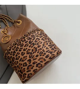 Detail of leopard print bucket bag featuring gold rose charm and chain drawstring