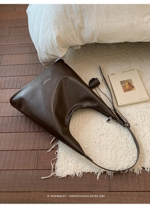 Detail der braunen Vintage-Ledertasche mit dezentem Logo auf weichem Hintergrund