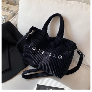 Close-up of black corduroy tote bag with TOTE BAG embroidery on a stylish office setting