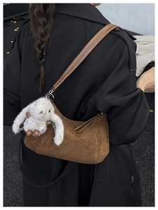 Detailed texture of brown suede crossbody bag with a cute white plush bunny charm