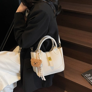 Sac seau beige en cuir motif litchi avec fermoir doré et pendentif ours stylé