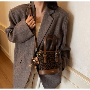 Détail du sac seau léopard avec base en cuir et porte-clés singe en peluche amusant