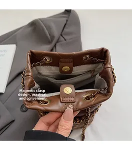 Detail of the magnetic buckle closure and leopard print base on a brown leather bucket bag