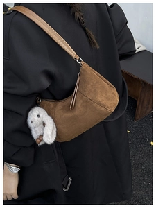 Detail of vintage brown suede hobo bag with a white bunny plush charm on strap