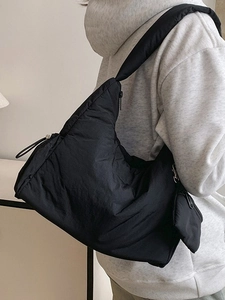 Black quilted puffer shoulder bag with detachable mini pouch for women on model