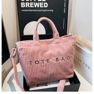 Detailed close-up of pink corduroy tote bag with embroidered letters and textured surface