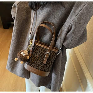Sac seau léopard porté avec un manteau en laine, vue sur la base en cuir et le profil