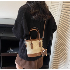Détail du sac seau en toile avec bordure en cuir marron et breloque monstre en peluche