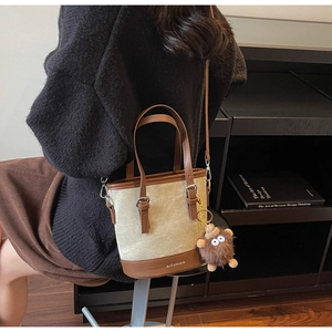 Détail du sac seau en toile avec garniture en cuir marron et breloque petit monstre