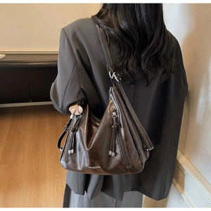 Detail of dark brown leather hobo bag with zipper accents and baseball keychain charm