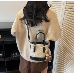 Détail du sac seau en toile et cuir avec breloque en fourrure sur la bandoulière