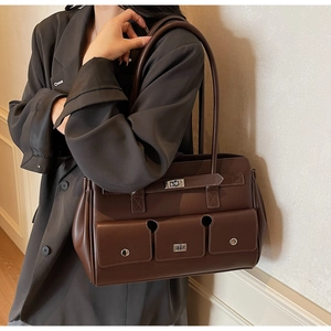 Detail view of brown leather bag with three cargo pockets and silver turn-lock hardware