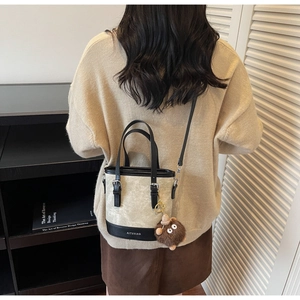 Détail du sac seau bicolore avec texture suédée et base en cuir griffée avec charm