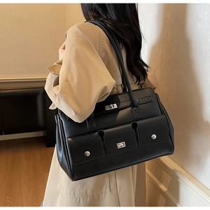Model wearing a black matte shoulder bag featuring three silver twist-lock front pockets