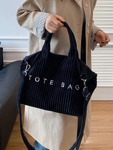 Black corduroy tote bag with TOTE BAG embroidery and adjustable shoulder strap on model