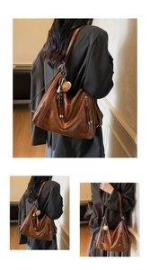Detail of vintage brown leather tote bag featuring a cute bear pendant and side zipper