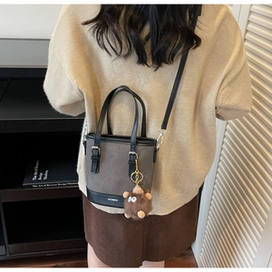 Détail d'un sac seau bicolore gris et noir avec un charmant monstre en peluche porté