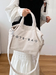 Minimalist white corduroy tote bag with black embroidery on a home interior background