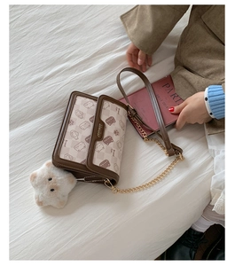 Detail view of cartoon print flap bag with leather trim and star plush charm on a bed