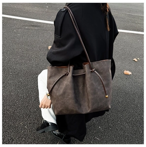 Detailed view of a large vintage tote bag in dark grey suede worn by a model