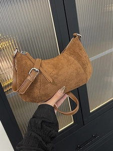 Brown faux suede hobo bag with adjustable strap and silver zipper shown held by hand
