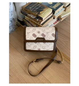 Close-up of Bread Cat print and metal logo on a vintage patchwork crossbody bag