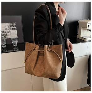 Detail of caramel tote bag featuring drawstring closure and gold metal ball accents
