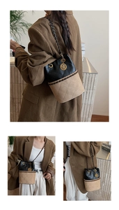 Detail of two-tone quilted bucket bag with chain strap and vintage gold pendant