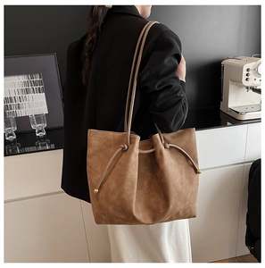 Close-up of brown faux suede tote bag featuring drawstring detail and gold metal accents