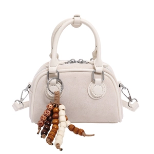 Cream vintage boston bag in matte suede with wooden bead charm on a white background