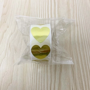 Close-up of golden heart-shaped self-adhesive seal stickers in a roll on wood surface