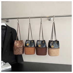 Detail of four chain bucket bags in mixed colors and textures hanging on a display