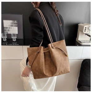 Brown faux suede tote bag featuring unique knot detail and gold spherical metal fastener