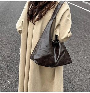 Détail d'un grand sac cabas en cuir souple marron porté avec un trench-coat classique