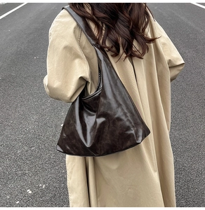 Détail d'un grand sac cabas marron foncé avec finition texturée porté sur un trench-coat