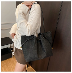 Detail of black matte tote bag with drawstring knots and elegant gold metal accents