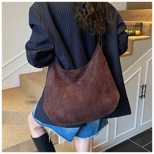 Detail of dark brown suede tote bag worn as an underarm bag for casual urban style