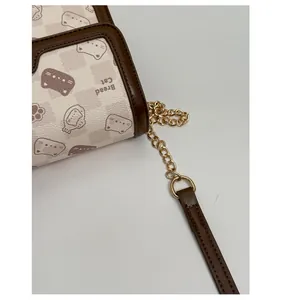 Detail of gold metal hardware and brown leather trim on a cute cartoon crossbody bag