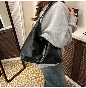 Vue latérale d'un grand sac cabas hobo en cuir noir souple porté par un mannequin