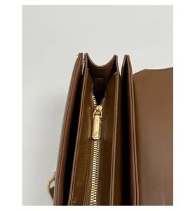 Detail view of the brown shoulder bag showing dual internal compartments and gold zipper