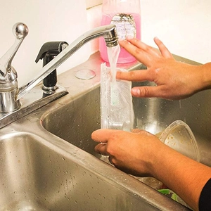 Waterproof food label stickers on transparent storage containers being rinsed under water