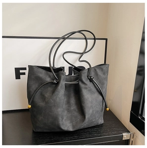 Detail of black suede tote bag with drawstring tassels and gold metal tips