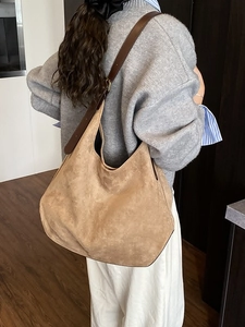 Minimalist large khaki suede tote bag with brown leather strap worn by a model