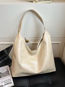 Grand sac cabas beige en similicuir souple pour le travail posé sur un banc en cuir élégant