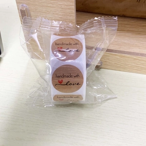 Detail of round kraft paper stickers roll featuring handmade with love text and red heart