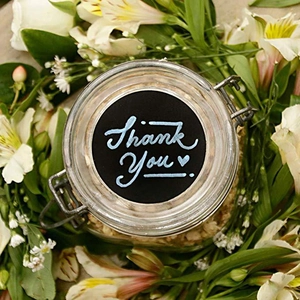 Top view of round black chalkboard label on a glass jar lid with white lilies around