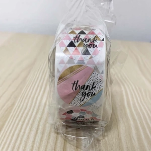 Detail view of round thank you stickers with geometric patterns in pink and gold