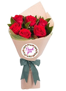 Close-up of a floral 'Thank you' sticker on a red rose bouquet wrapped in kraft paper